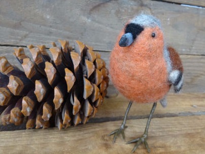 gefilzter Vogel mit Zapfen im Hintergrund