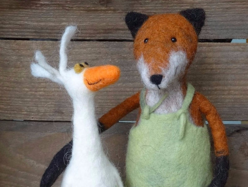 Ein gefilzter Fuchs mit Latzhose und eine gefilzte weiße Gans stehen nebenenander.