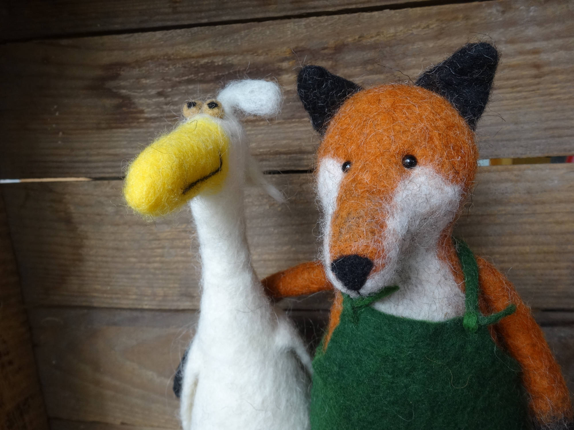 Ein gefilzter Fuchs mit grüner Latzhose neben einer weißen, gefilzten Gans.
