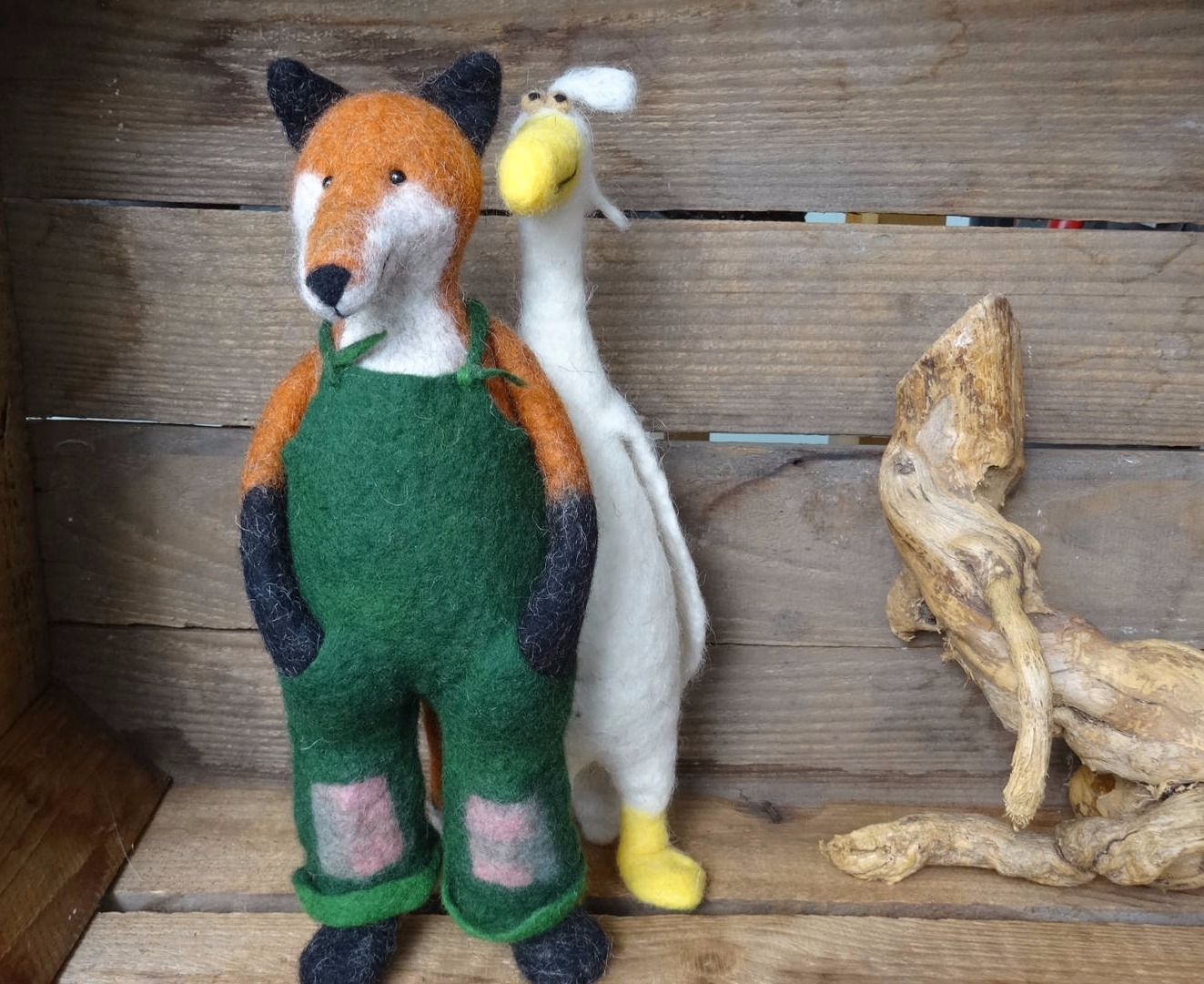 Gefilzter Fuchs mit grüner Latzhose und hinter ihm eine weiße gefilzte Gans.