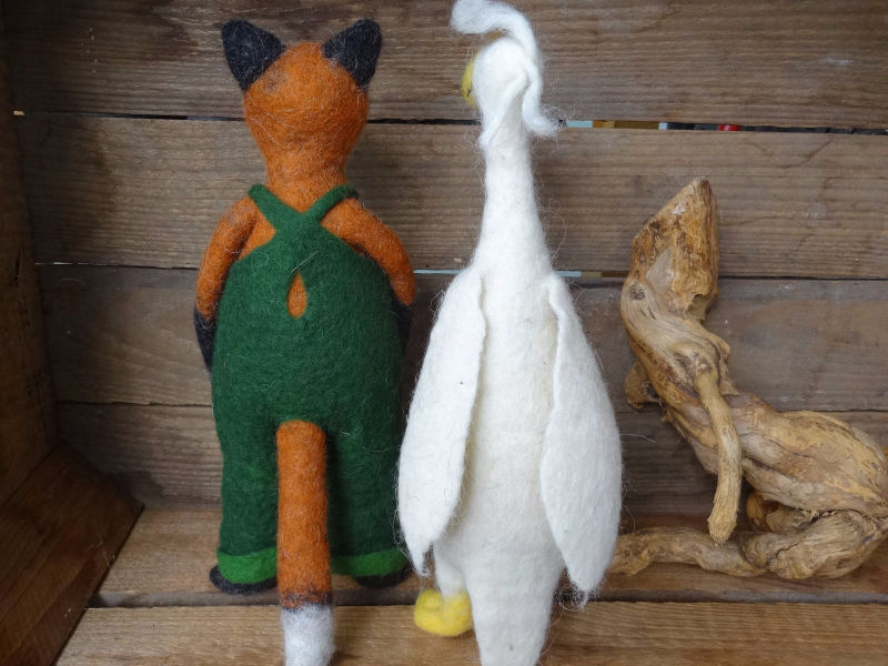Gefilzter Fuchs mit grüner  Latzhose und eine weiße, gefilzte Gans von hinten